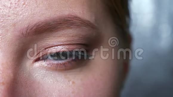 白种人女性的特写美丽的眼睛直视镜头眨眼室内灰色背景视频的预览图