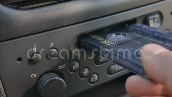 男人把盒式磁带插入旧的汽车盒式磁带播放器中视频的预览图