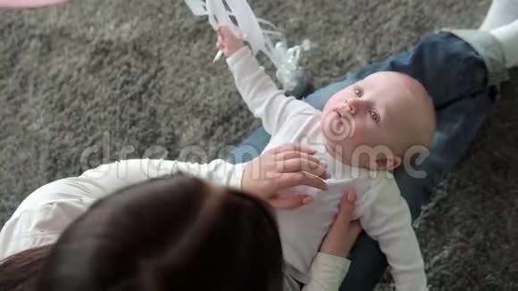 一位美丽的母亲和婴儿在地板上微笑的特写肖像视频的预览图