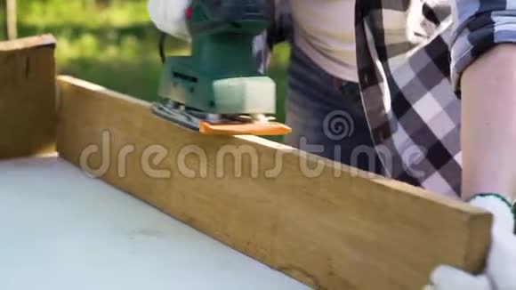 在工作手套上用电动砂光机将女性双手上的木板打磨干净视频的预览图