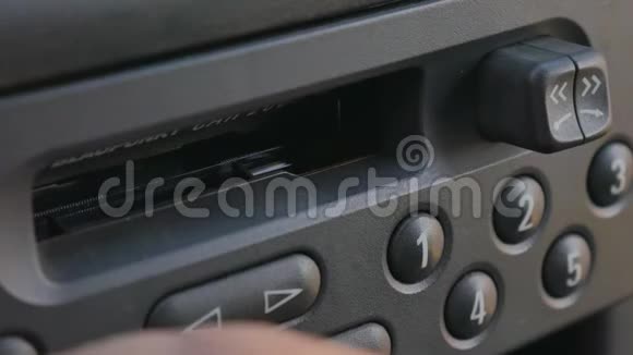 男人把盒式磁带插入旧的汽车盒式磁带播放器中视频的预览图
