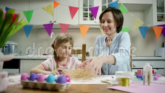 母女俩坐在桌边用彩蛋做窝视频的预览图