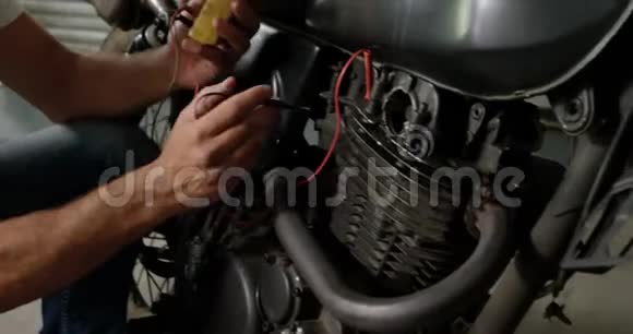 男机修工在维修车库4k检查摩托车电池视频的预览图