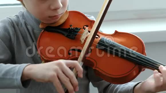 拉小提琴无法辨认的七岁男孩在拉小提琴特写前景视频的预览图