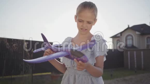 肖像可爱的小女孩玩小玩具飞机特写孩子在后院里呆在户外视频的预览图