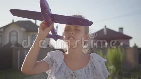 一个漂亮可爱的小女孩玩小飞机特写的肖像孩子在户外的时候视频的预览图
