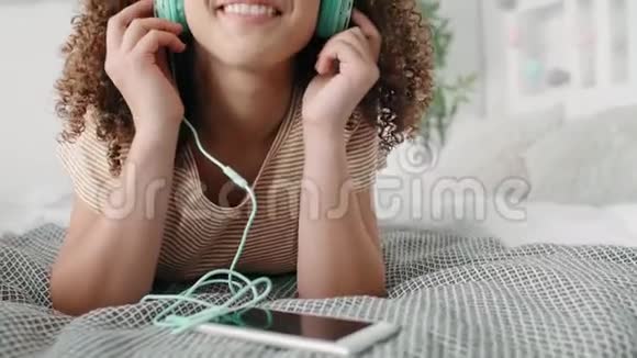 在床上听音乐的年轻女子视频的预览图