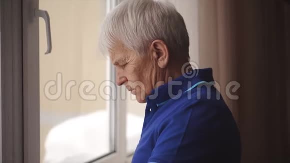孤独的老人戴着眼镜站在窗边视频的预览图