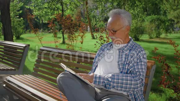 公园里坐在长椅上看书的老人视频的预览图