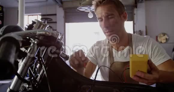 男机修工在维修车库4k检查摩托车电池视频的预览图