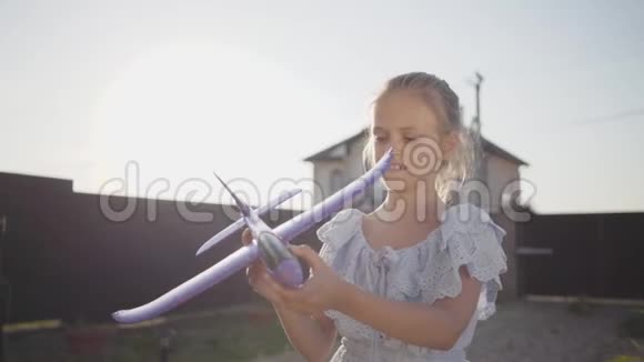 肖像漂亮的小女孩玩小玩具飞机特写孩子在后院里呆在户外视频的预览图