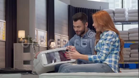 一对漂亮的夫妇一起在家具店里挑选矫形床垫视频的预览图