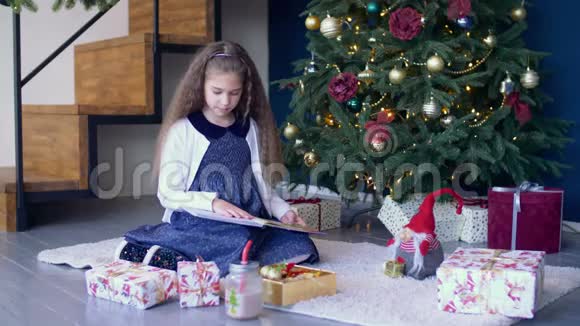 积极的女孩在圣诞树下看书视频的预览图