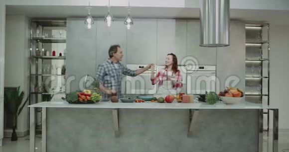 有趣的是一对成熟的夫妇在现代厨房边做食物边跳舞视频的预览图