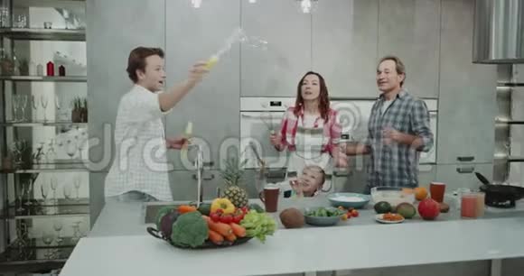 有魅力的家庭成熟的父母和两个孩子有一个家庭时间一起在厨房玩泡泡而视频的预览图