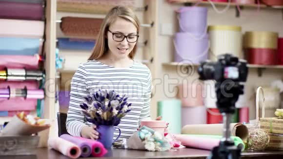 在花店里年轻的花店女用纸包花她试图谱写花朵视频的预览图