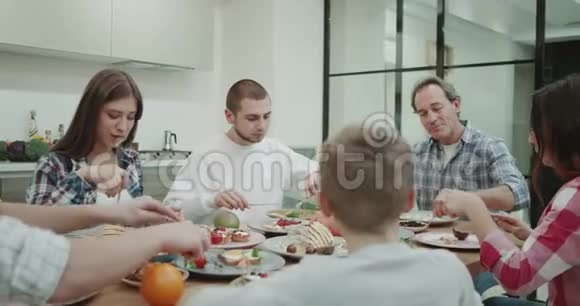 吃饭时间为一个大家庭供应和吃饥饿的食物并有一个伟大的气氛在现代厨房视频的预览图