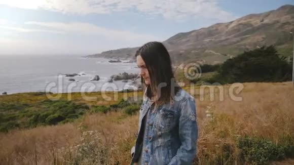 年轻美丽悲伤的女人看起来沮丧走在史诗般的大苏尔海岸上长满了茂盛的黄花视频的预览图