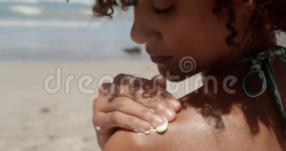 在4k阳光下在沙滩上涂防晒霜的女人视频的预览图