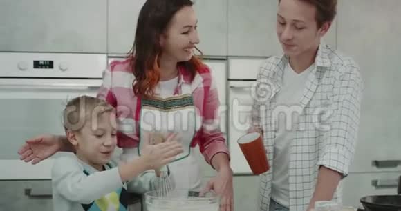 可爱的一家人一起准备早餐小男孩在现代厨房里用手搅拌器混合所有的配料视频的预览图