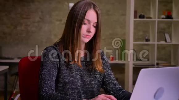 严肃的姜女商人的肖像在笔记本电脑屏幕上观看然后进入相机视频的预览图