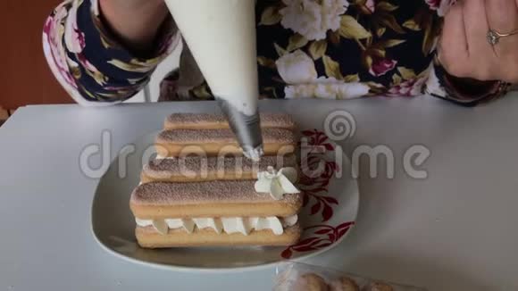 一个女人在萨沃亚迪饼干上涂上奶油用糕点包以鲜花的形式视频的预览图