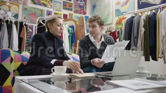 年轻人和成年妇女在笔记本上检查文件和写东西视频的预览图