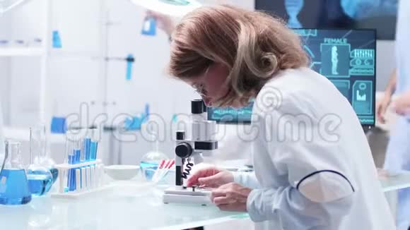 关闭女研究员在显微镜下观察的镜头视频的预览图
