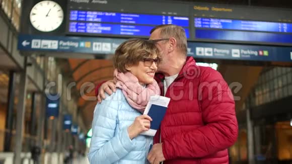 幸福成熟的夫妇在火车站的站台上笑着拥抱情人节家庭旅行视频的预览图
