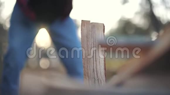 一个穿格子衬衫和牛仔裤的人把木头切成两块福斯特切木头视频的预览图