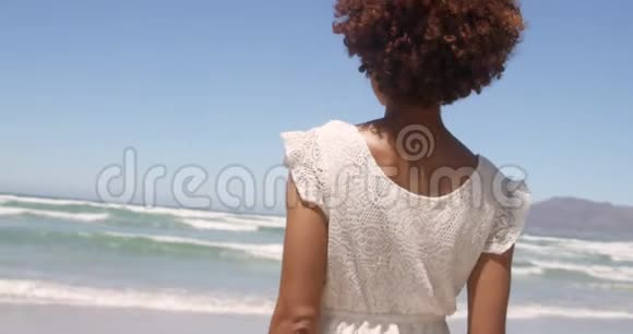 年轻的非洲裔美国妇女在阳光下海滩散步的后景视频的预览图