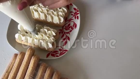 一个女人在萨沃亚迪饼干上涂上奶油用糕点包以鲜花的形式视频的预览图