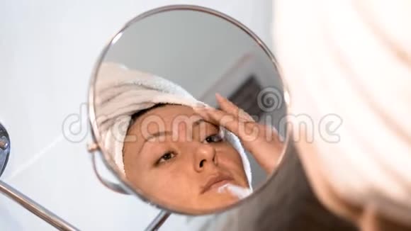 那个女人把面霜涂在皮肤上化妆镜前的白种人女性视频的预览图