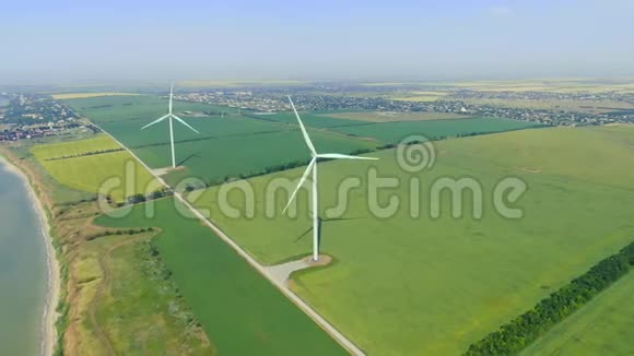 风电场在靠近大海的一个绿色大田的空中镜头视频的预览图