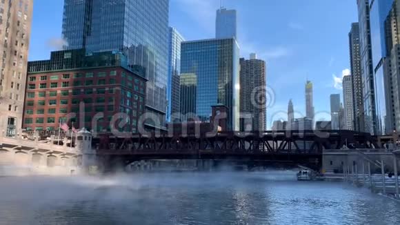 蒸汽从芝加哥河上升随着温度下降和一个高架埃尔火车通过一座桥视频的预览图