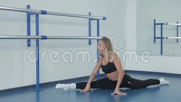 漂亮的年轻女子坐在地板上做伸展运动在一间色彩鲜艳的运动厅里做瑜伽视频的预览图
