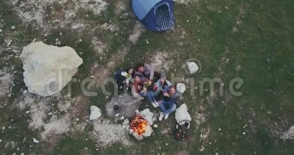 无人机捕捉一群朋友在大自然中度过美好的时光在篝火上喝酒快乐有难忘的时光视频的预览图