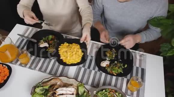 在厨房的餐桌上作为夫妻的家庭晚餐桌子上有沙拉玉米和青豆视频的预览图