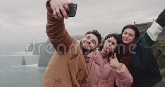 漂亮的朋友多民族用智能手机在摩赫悬崖上拍照他们很搞笑视频的预览图