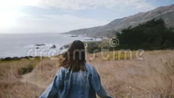 镜头跟随年轻女子走在大海沿岸长满了黄花对着镜头欢快地笑视频的预览图