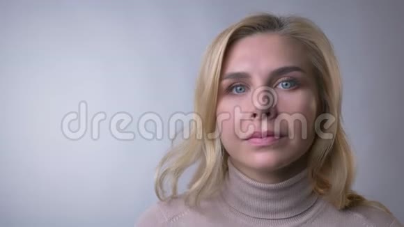 一位中年金发女子的特写镜头招手在灰色背景上抬起眉毛视频的预览图
