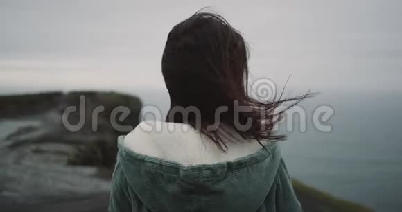 在悬崖顶上一个黑发女人冥想她欣赏周围的风景并对风景印象深刻视频的预览图
