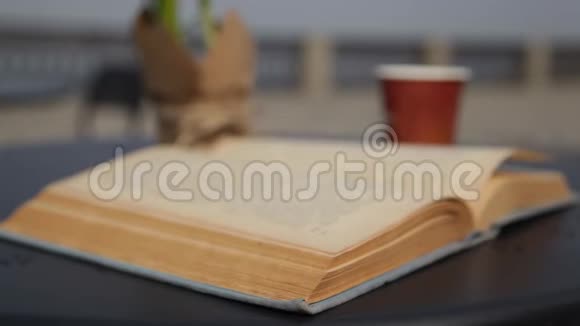 风把一本旧书的书页吹翻了早晨咖啡和户外旧纸书的视频视频的预览图