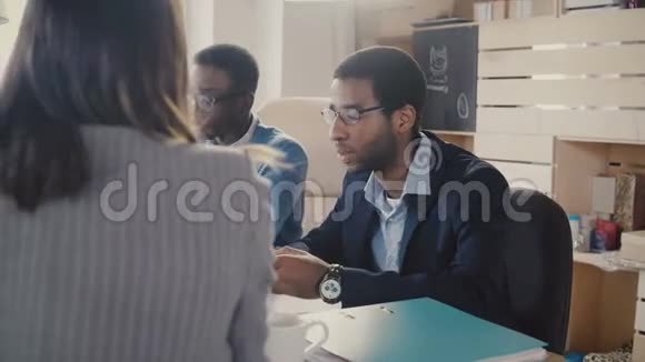 两个紧张的非裔美国人经理坐在桌子旁听着无法辨认的女律师在办公室会议4K视频的预览图