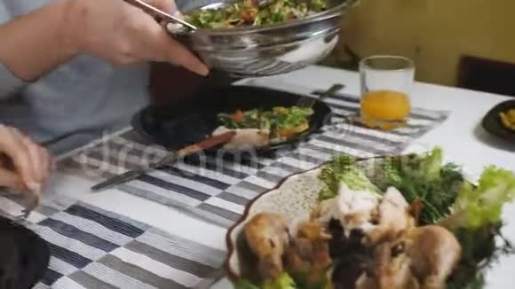 家庭晚餐一对夫妇一起在厨房吃晚饭那个男人把沙拉放在盘子里给他的妻子视频的预览图