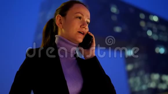 忙碌的女人用手机对着市中心的现代摩天大楼说话视频的预览图