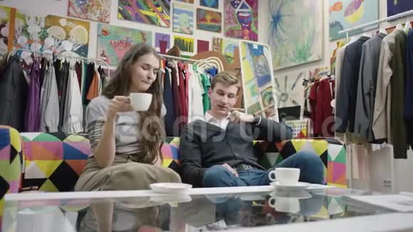 一对年轻夫妇在服装店里一边喝咖啡一边聊天视频的预览图
