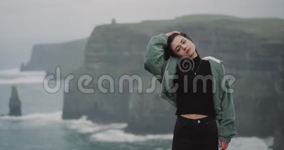 美丽的女士站在镜头前站在莫赫悬崖的岸边魅力四射直视着视频的预览图