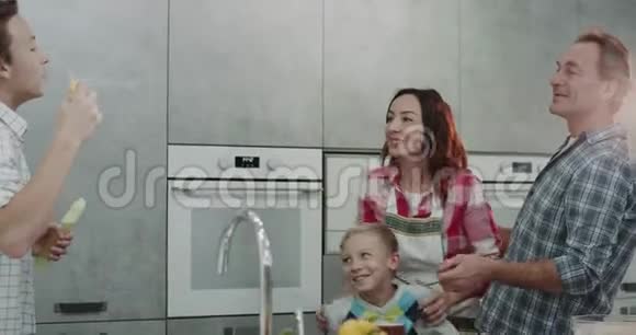 爸爸和妈妈和他们的两个儿子在一个现代化的厨房里玩有趣的泡泡一天视频的预览图