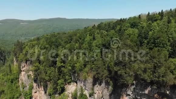 在一个有高崖密林和河流的深岩石峡上观看相机飞行的空中景色视频的预览图